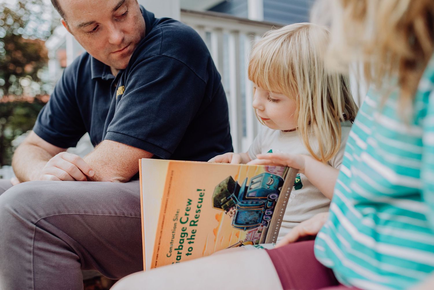 A group of people reading a storybook together while sitting on a couch.