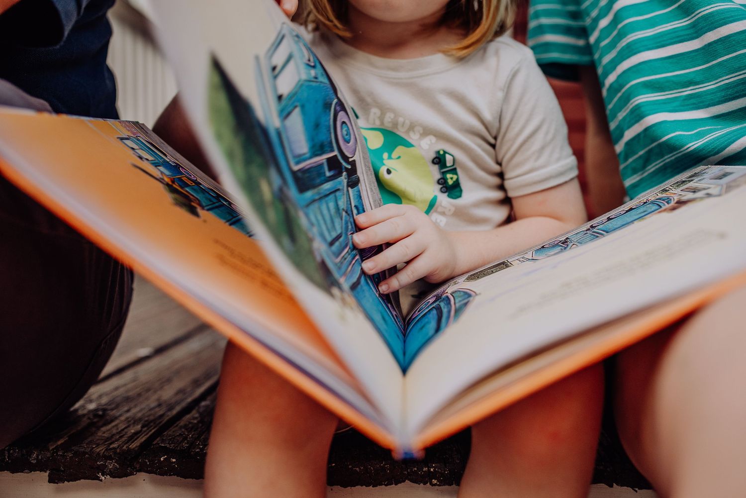 Close-up view of hands holding books and reading materials in a learning environment.