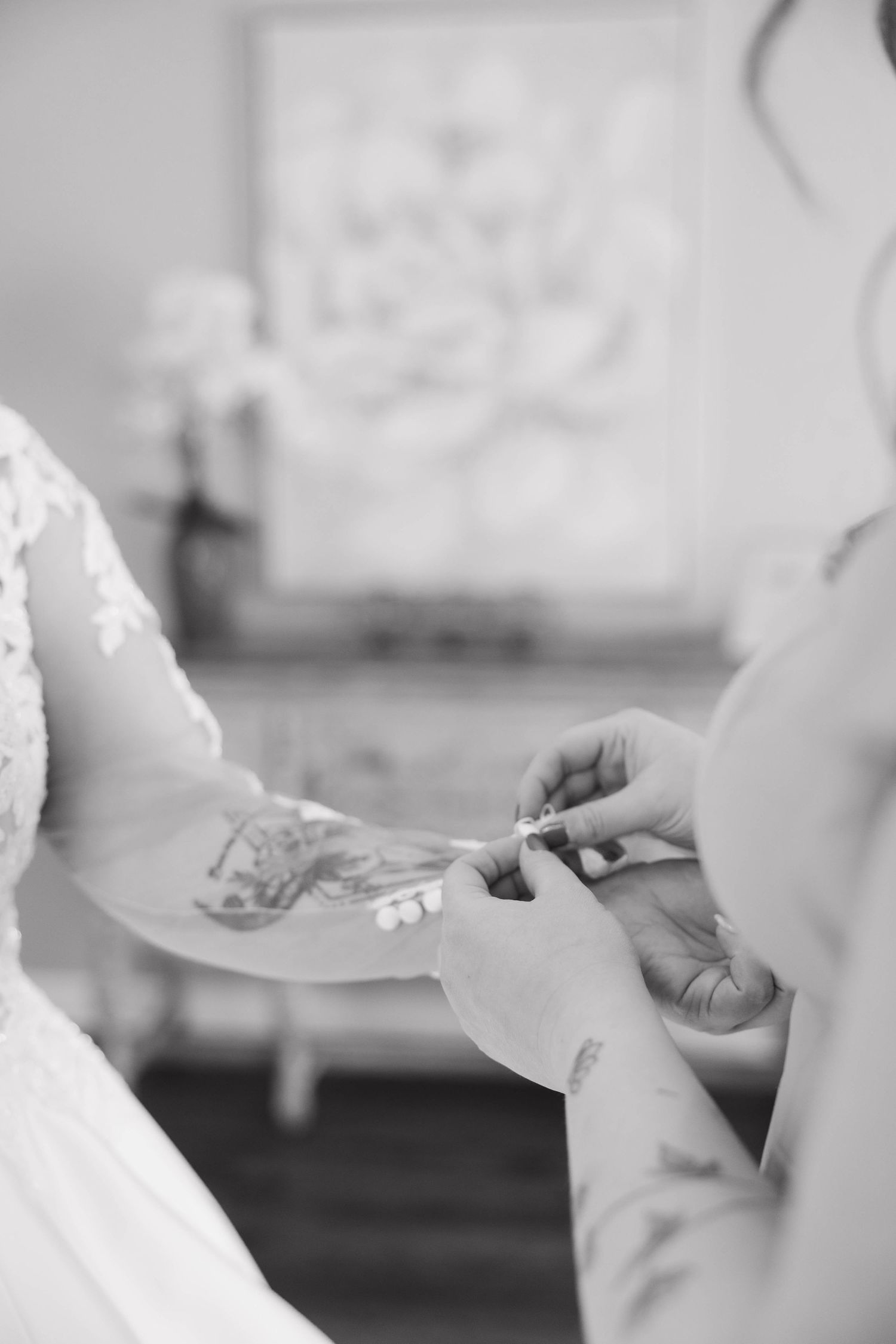 Close-up black and white photo of hands exchanging wedding rings during ceremony.