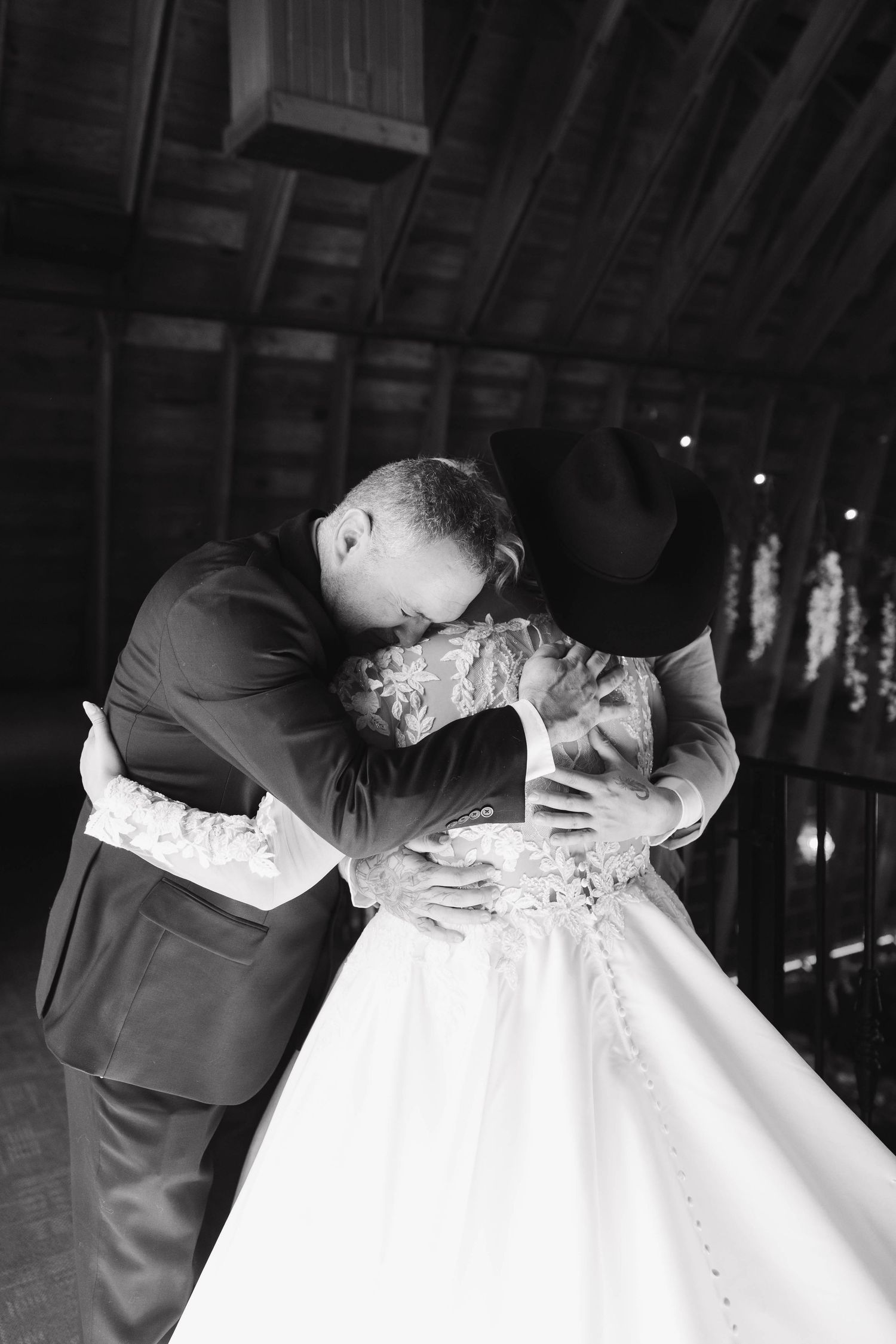 Romantic black and white wedding photo showing a tender kiss between a couple in formal attire.
