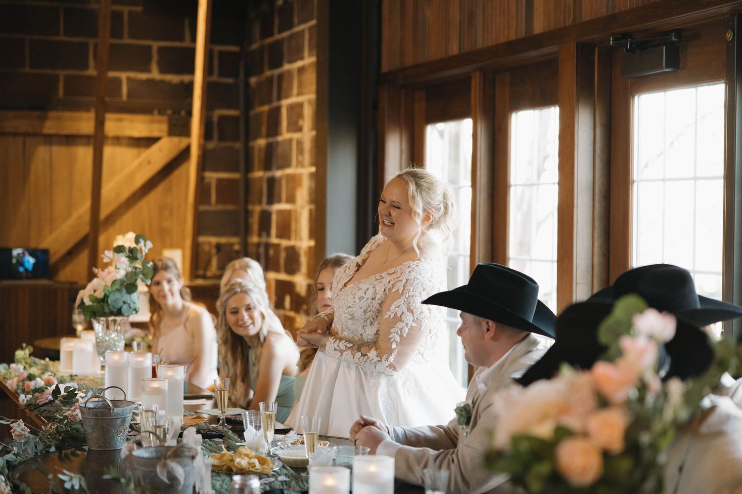 Rustic barn wedding reception setup with wooden beams and natural lighting streaming through windows.