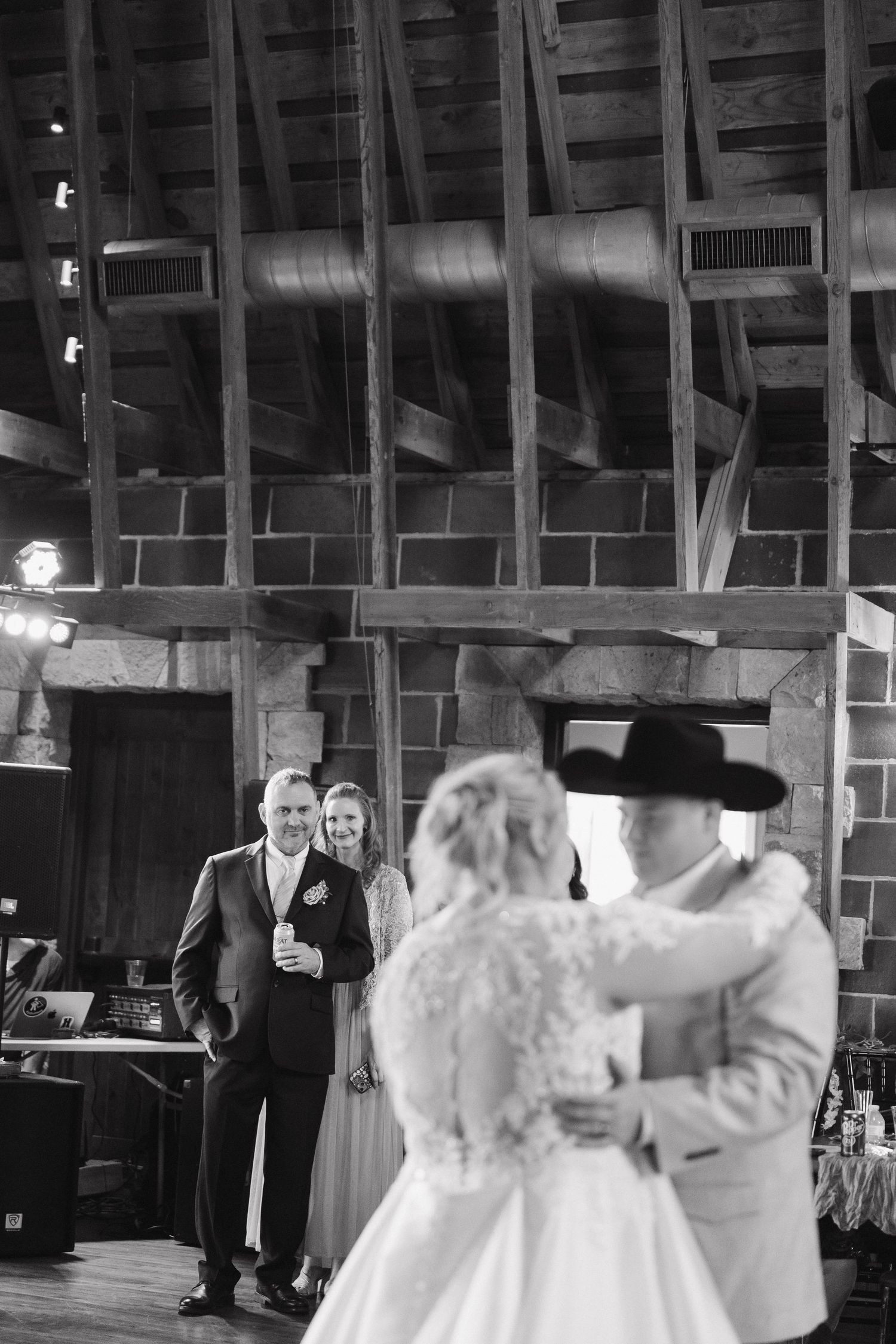 Black and white photo of wedding dance in rustic venue with exposed brick walls.