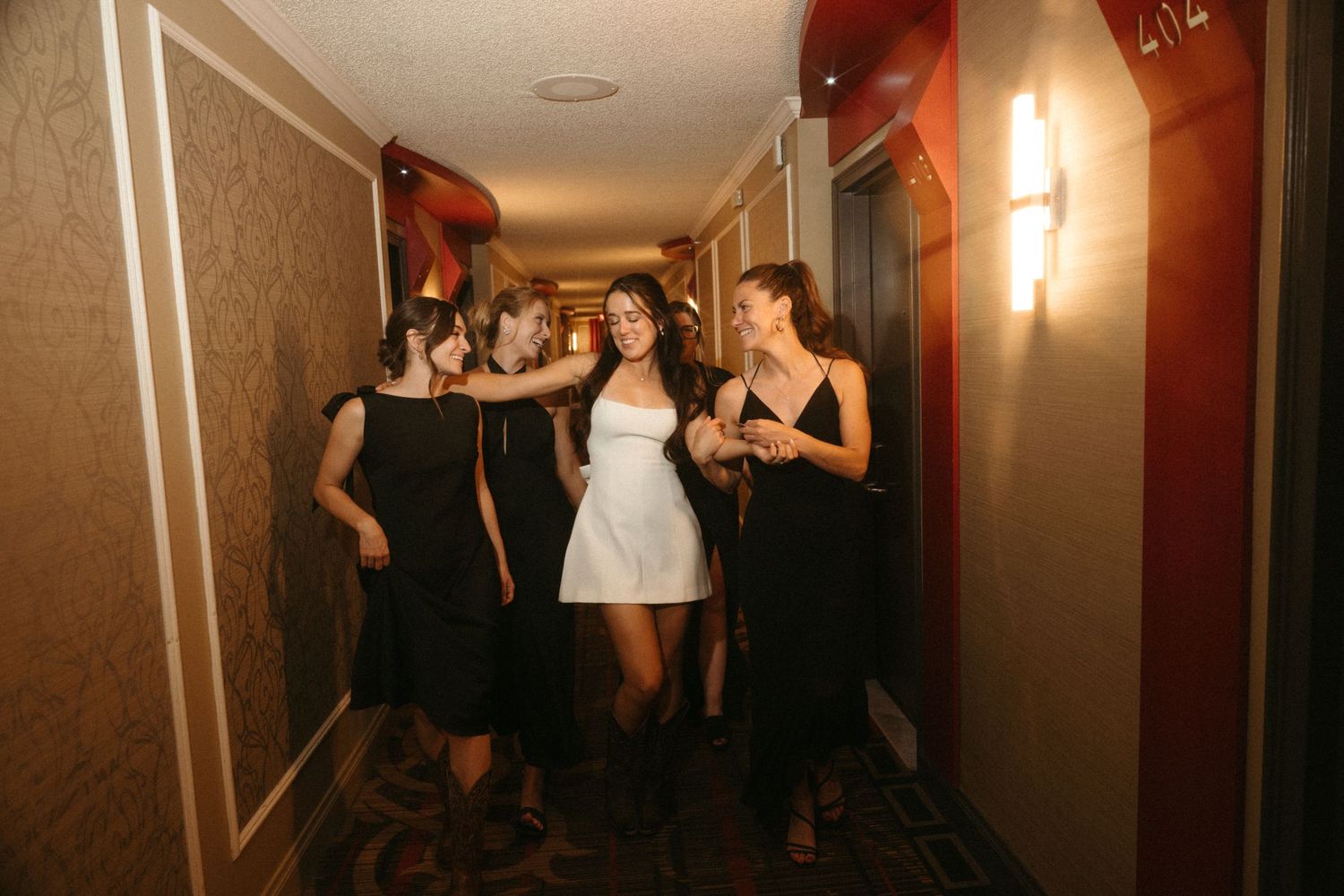 A group of people walking together in a hallway, some wearing formal attire.