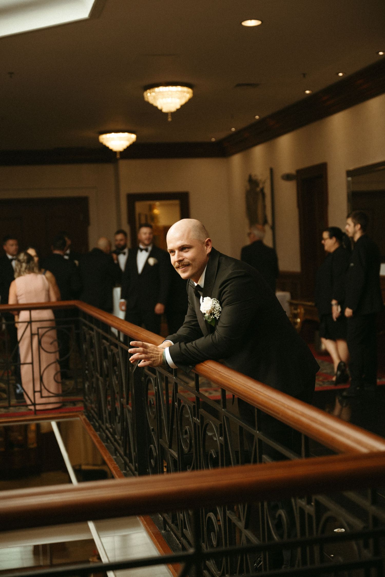 A man in a suit standing on a staircase in a formal setting.