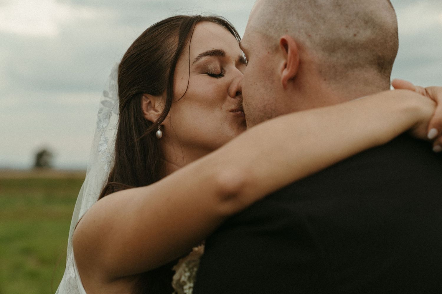 A bride and groom embrace and kiss passionately on their wedding day.