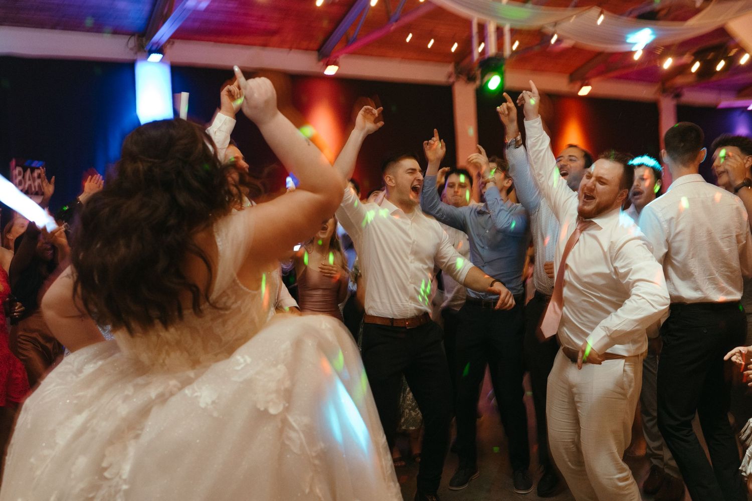Bride and wedding guests dancing and celebrating on the dance floor during a lively wedding reception.