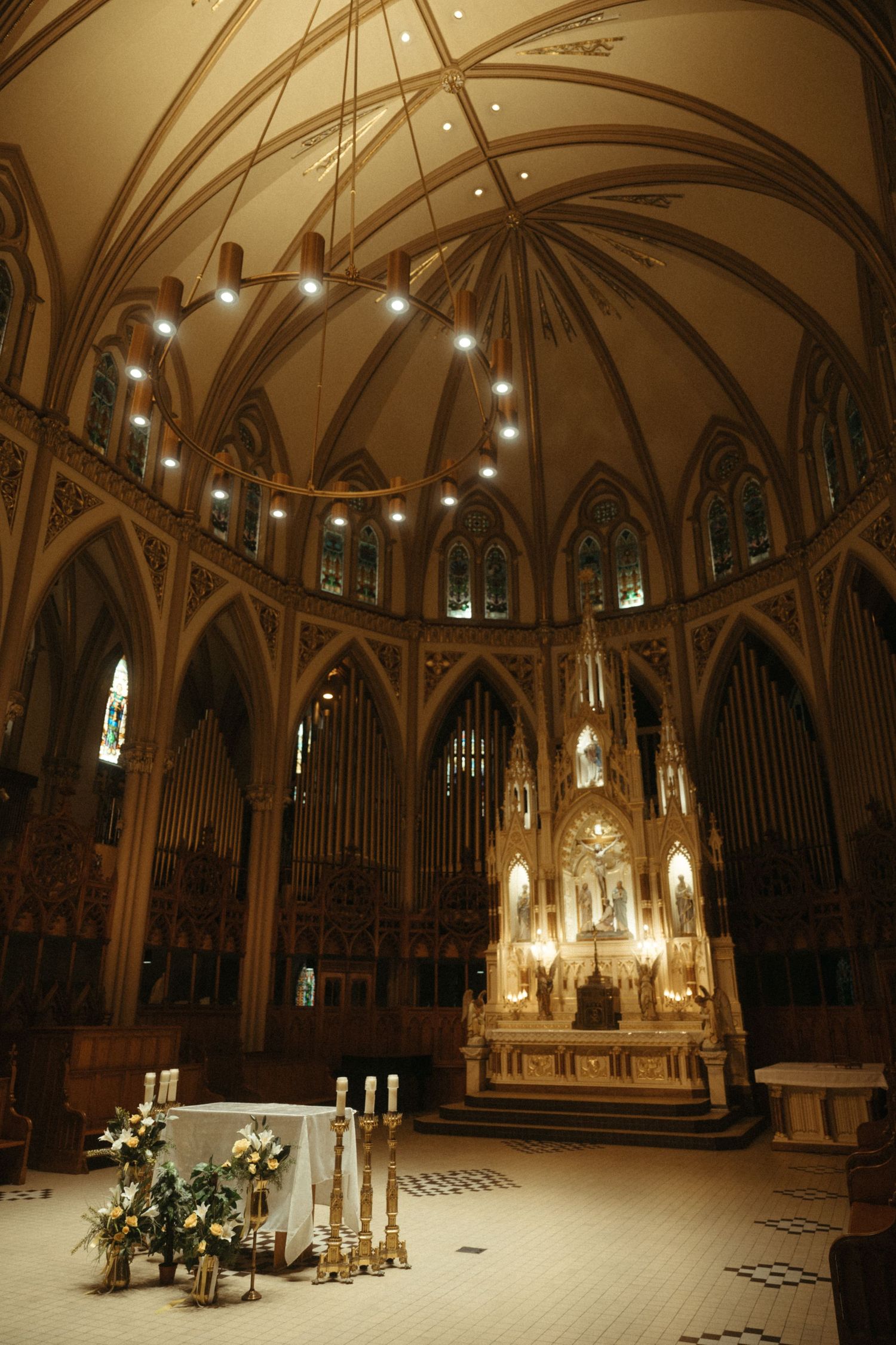 Gothic cathedral interior with vaulted ceiling, ornate altar, candles, and floral arrangements for a wedding ceremony.