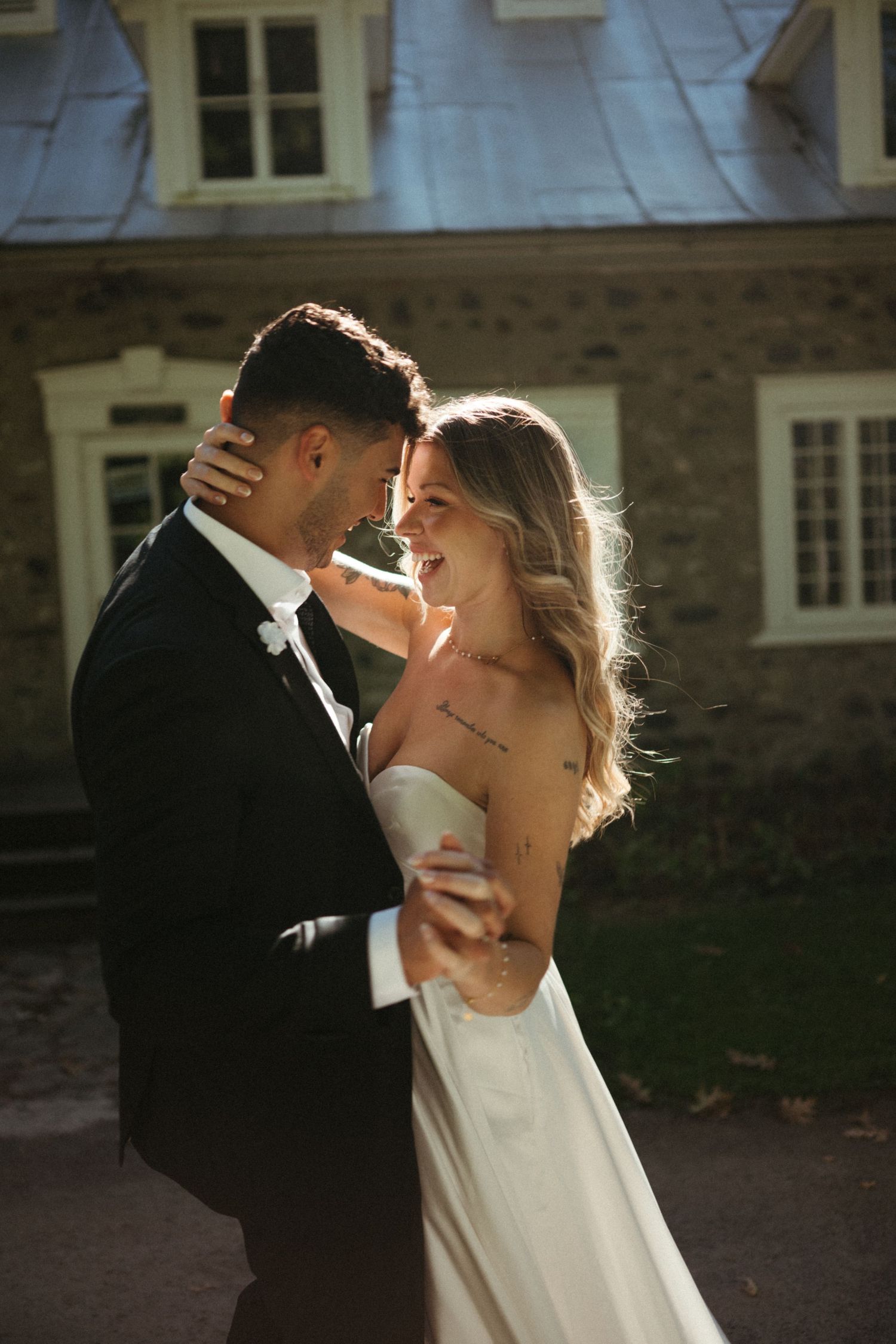 A bride and groom embrace affectionately in front of a historic building.