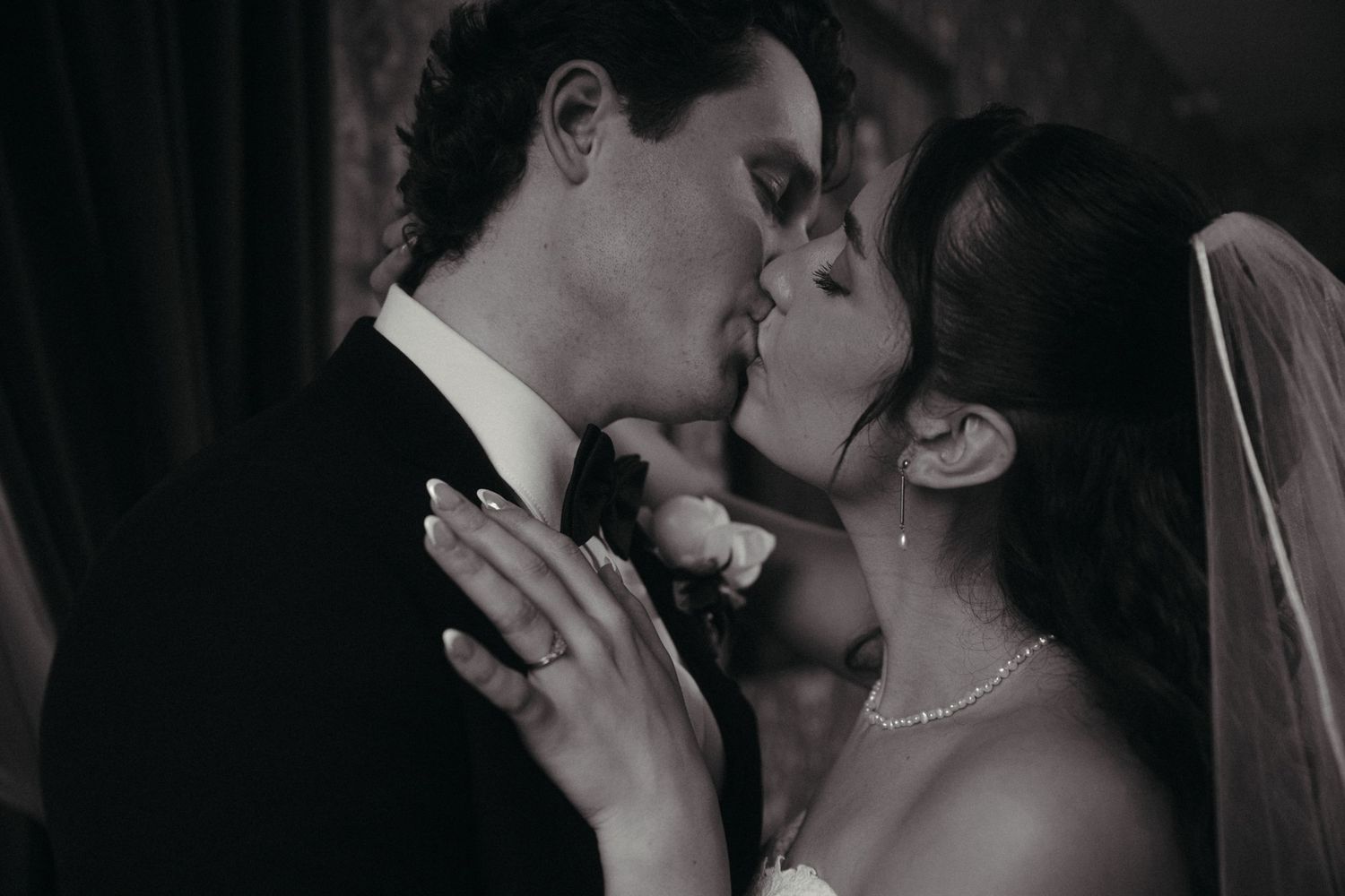 Black and white close-up of a bride and groom sharing a romantic kiss on their wedding day.