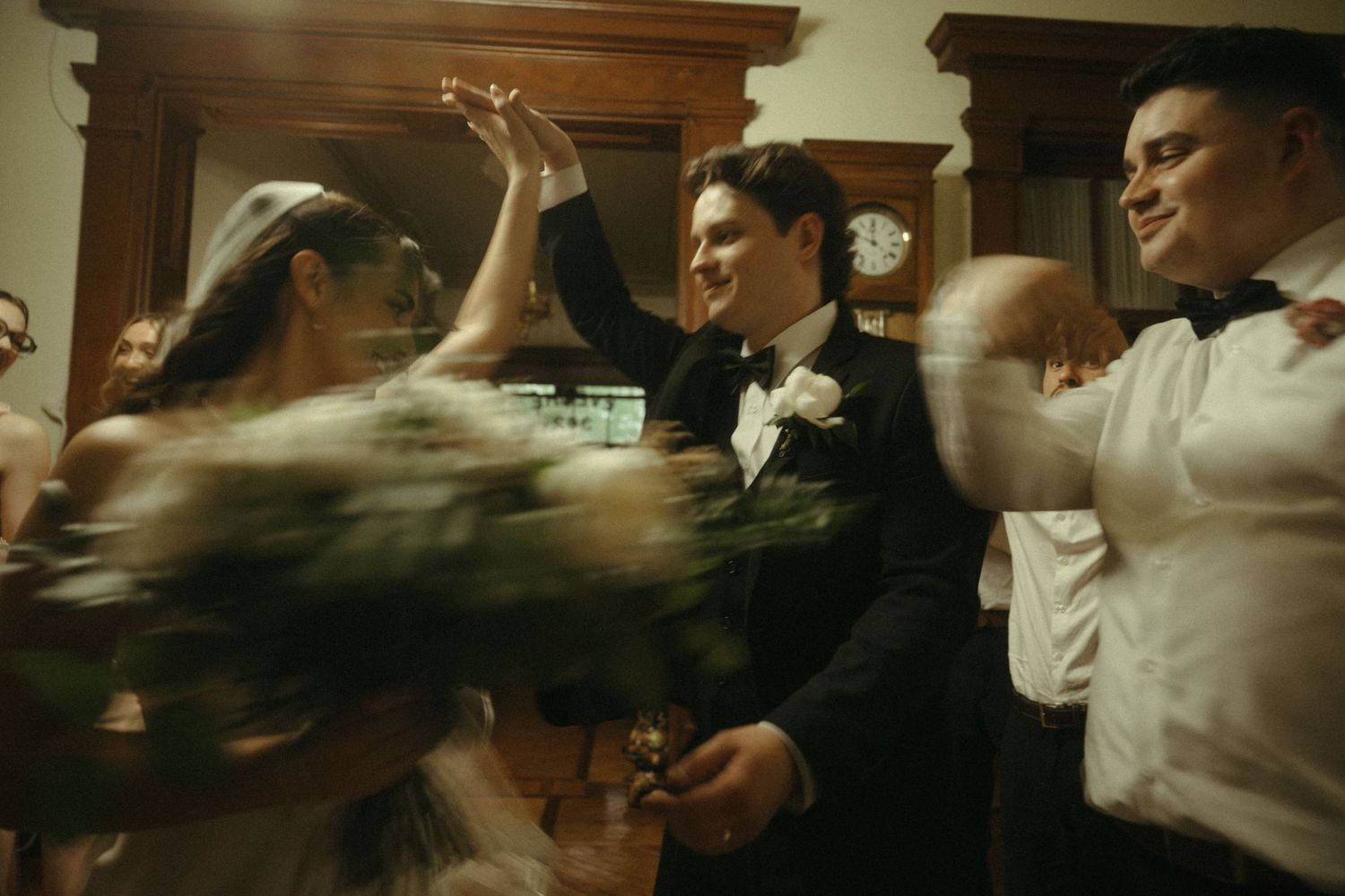 Bride and groom celebrating joyfully with guests during lively wedding reception dance.