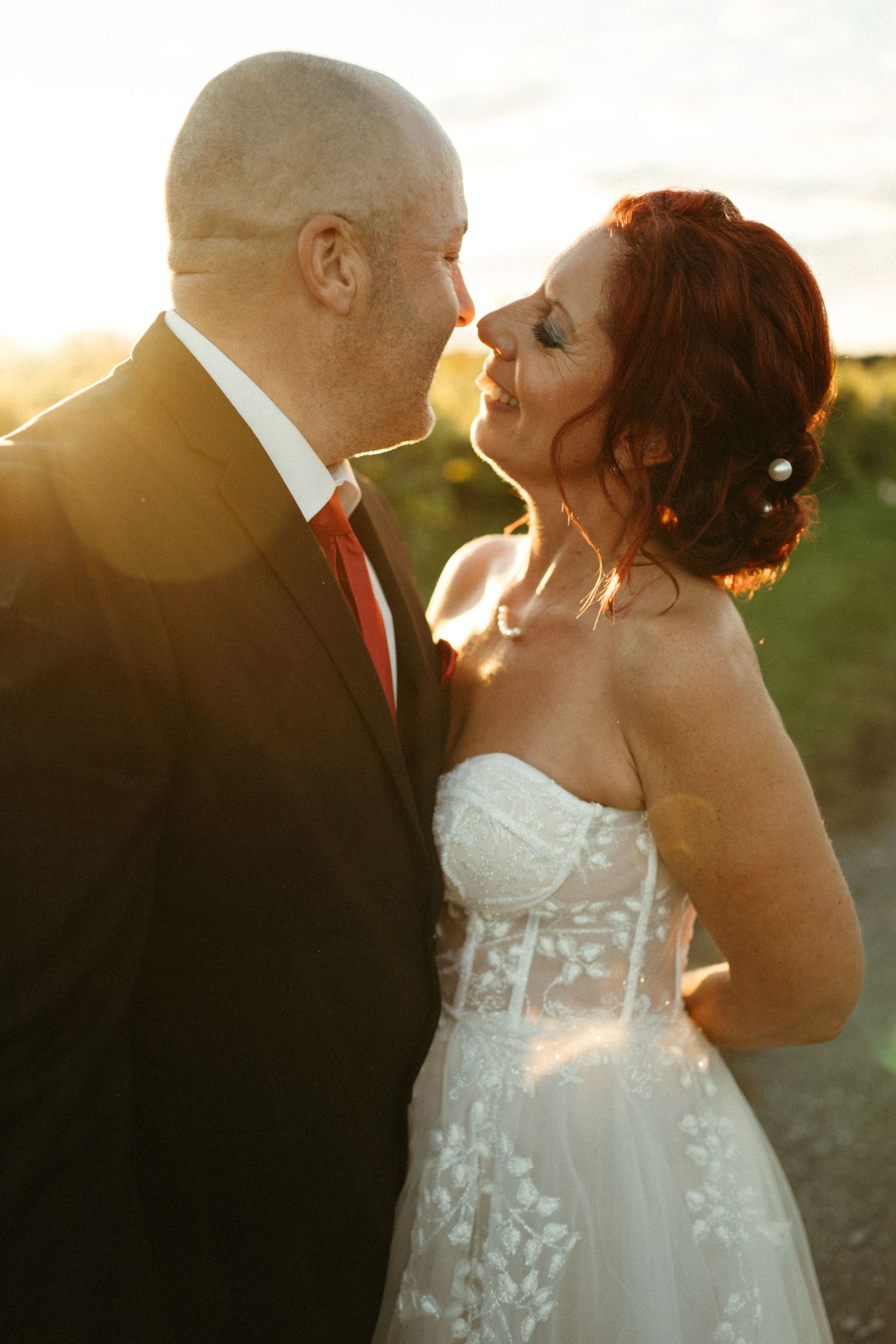 A bride and groom share a romantic moment at golden hour, with warm sunlight glowing behind them at their wedding.