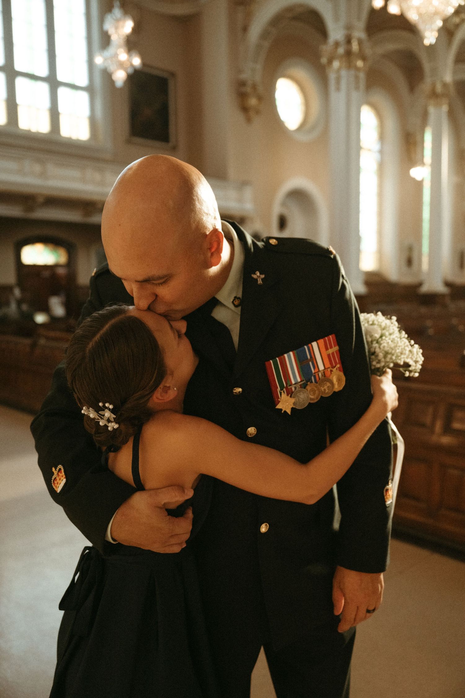 Military groom in uniform kissing bride in church after wedding ceremony.