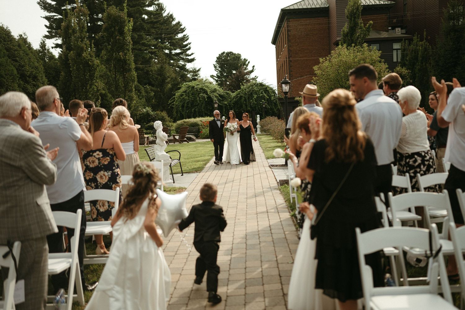 Outdoor wedding ceremony with guests seated in white chairs as couple exchanges vows.