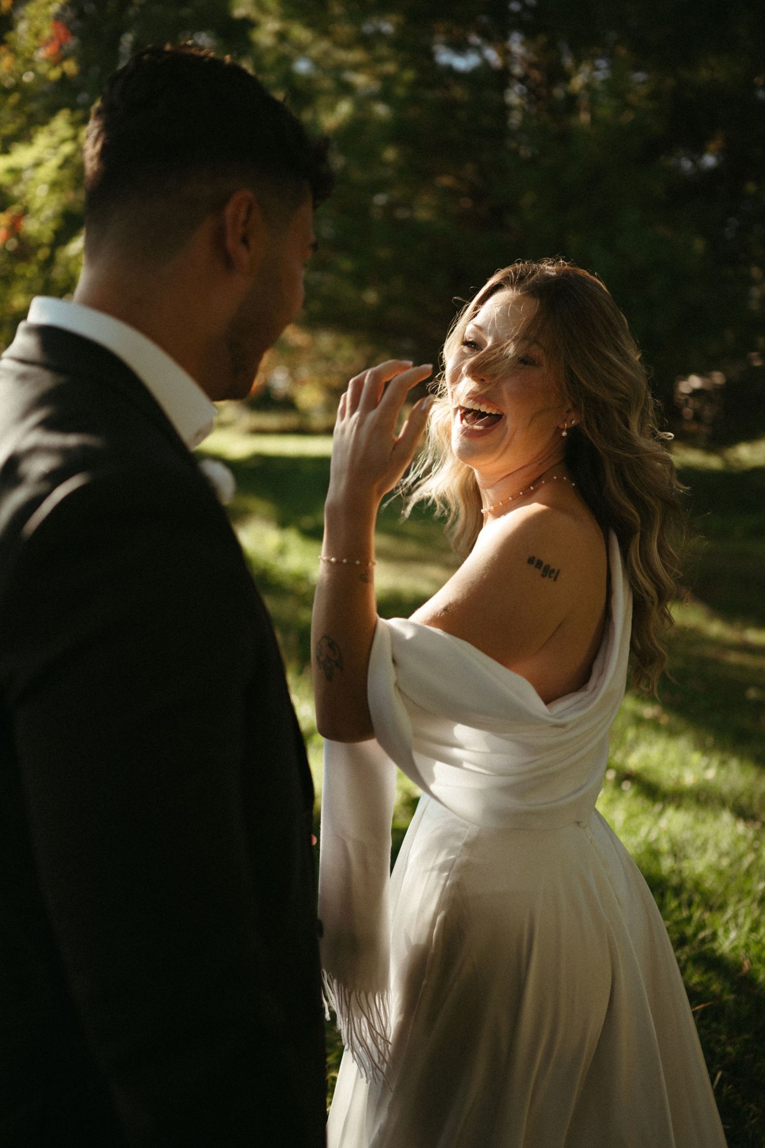 A bride and groom embrace and smile at each other in a scenic outdoor setting.