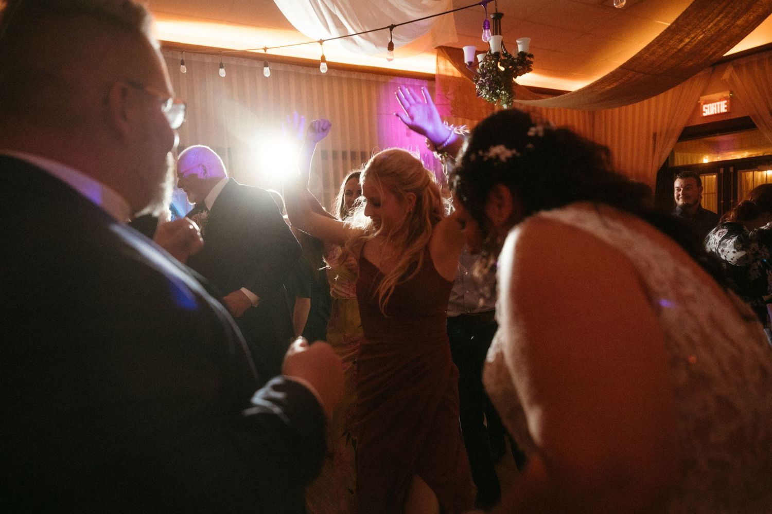 Bride and guests dancing energetically on the wedding reception dance floor.