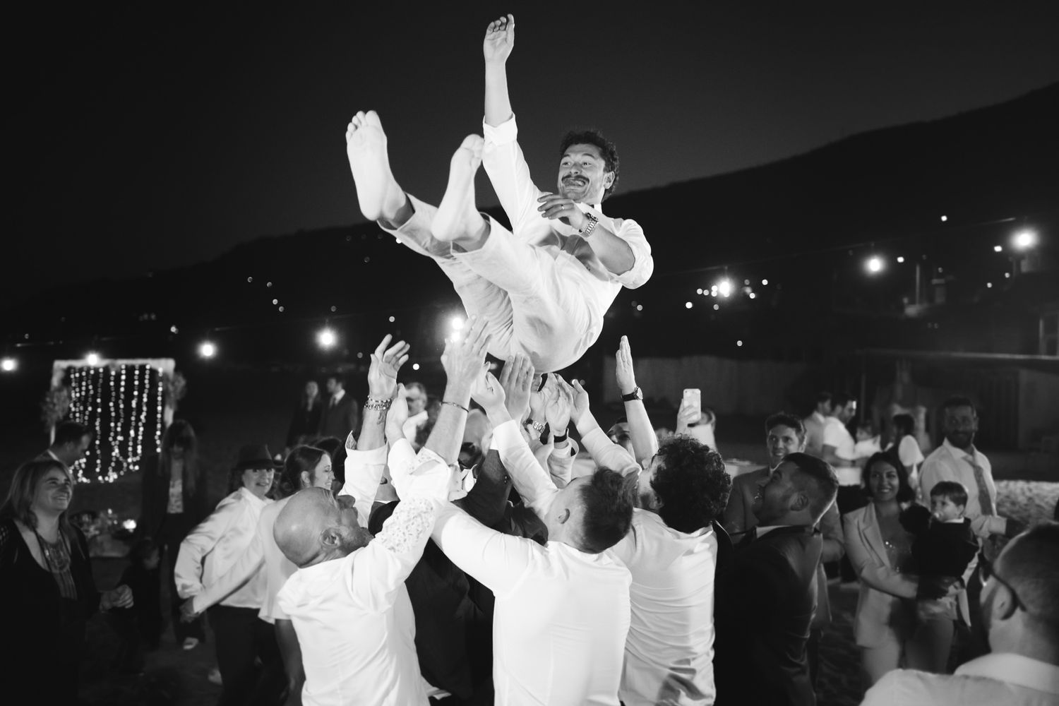 lo sposo viene lanciato dagli amici in aria in una foto di matrimonio divertente in spiaggia a Sanremo