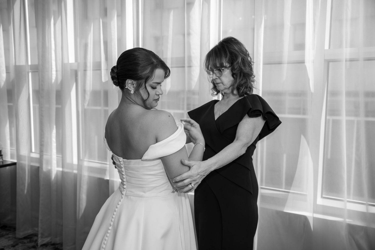 A romantic couple shares an intimate dance moment in front of sheer white curtains in a sunlit room.