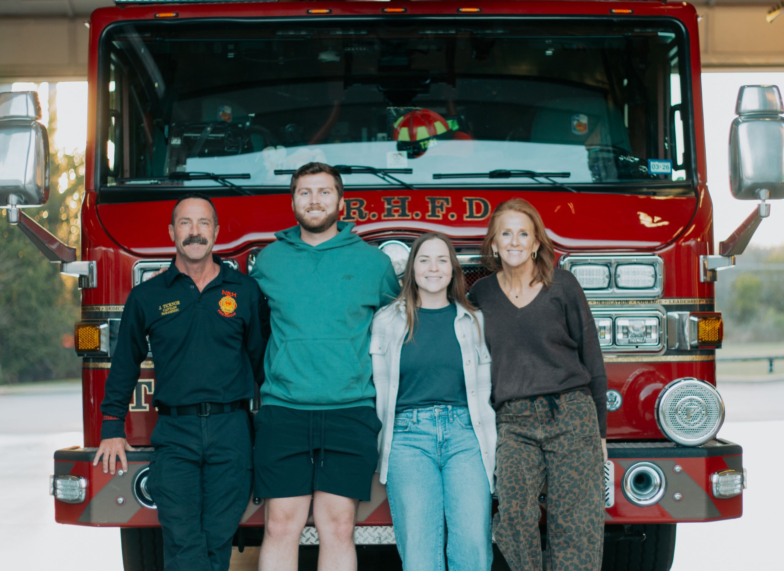 A group of people posing in front of a red fire truck in a series of five similar photos.
