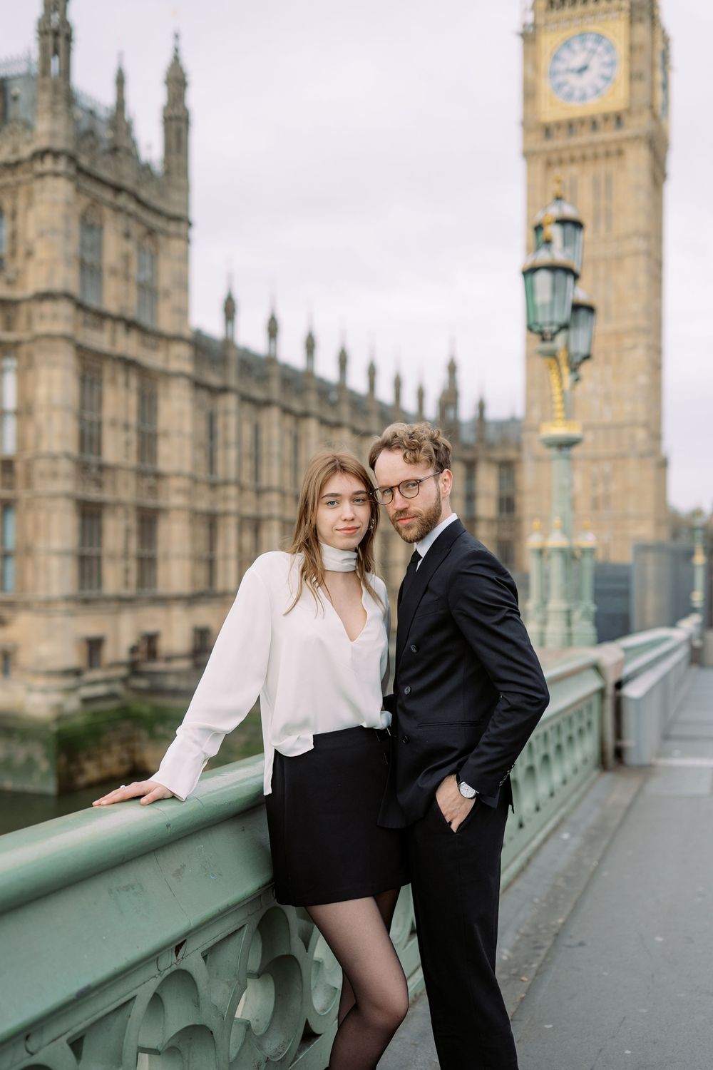 A couple poses together on Westminster Bridge with Big Ben and the Houses of Parliament in the background.