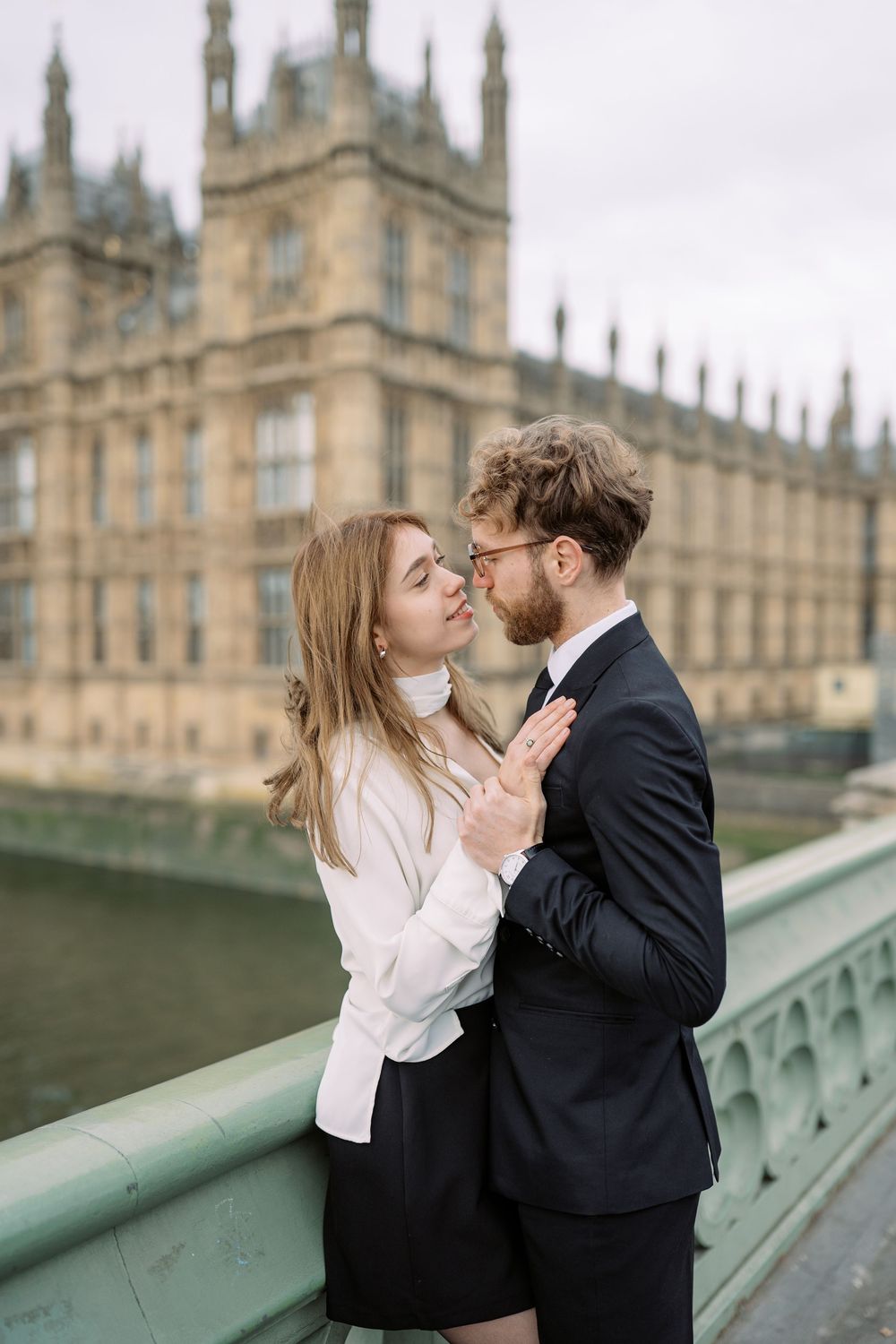A romantic couple shares intimate moments on Westminster Bridge with the Houses of Parliament in the background.