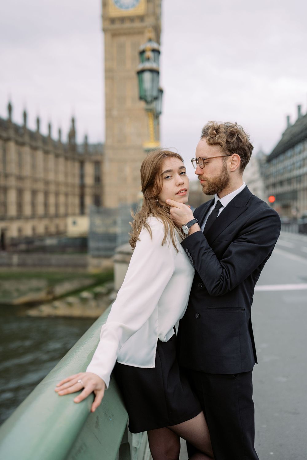 A couple shares romantic moments by the River Thames with Big Ben and Parliament in the background in London.