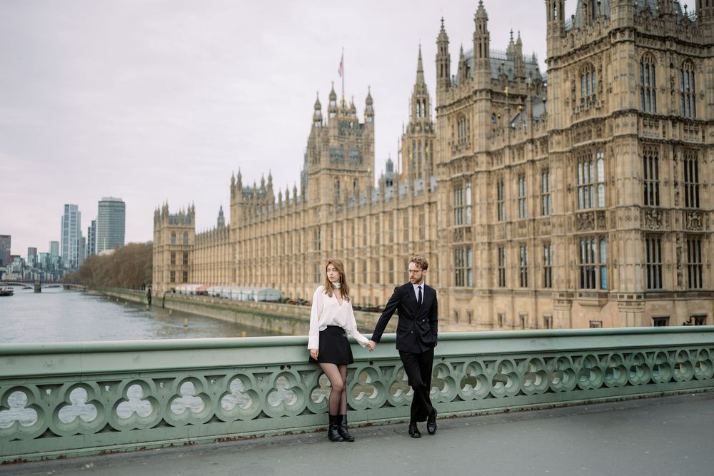 People walking near the Houses of Parliament in London with Westminster Palace and Big Ben in the background.