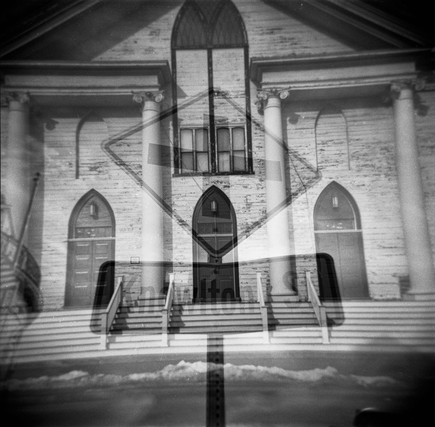 A black and white panoramic view of a historic building facade with columns and symmetrical architecture.