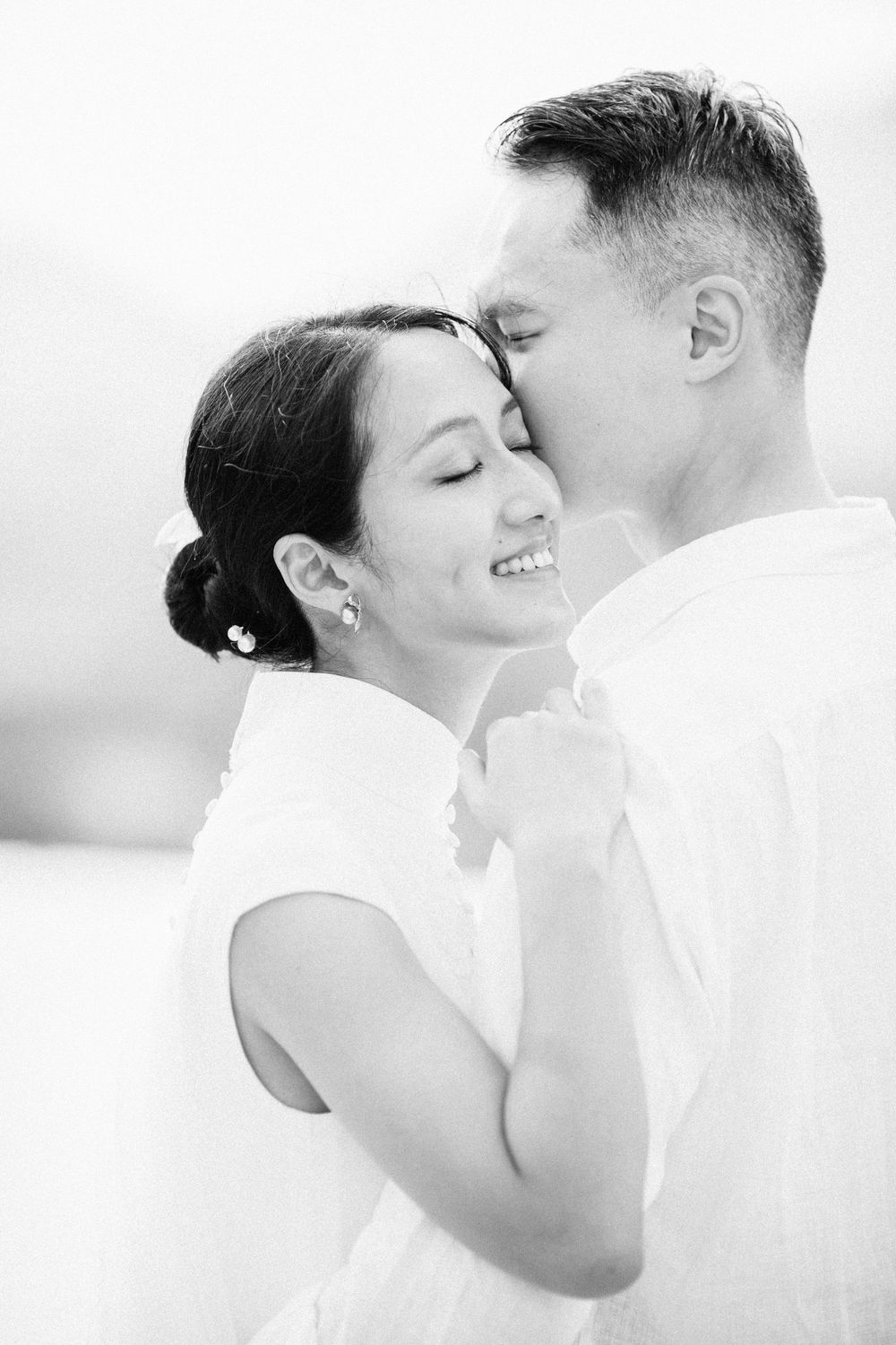 intimate black-and-white wedding portrait of groom kissing bride in a white cheongsam at a Koh Samui destination wedding