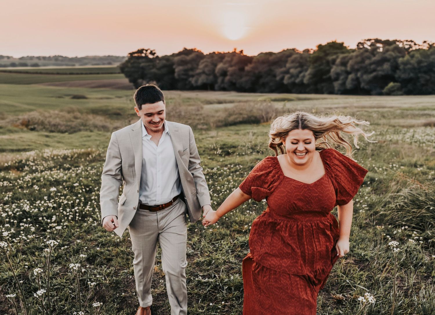 Couple walking through tall green grass during engagement session at Murrell Park.