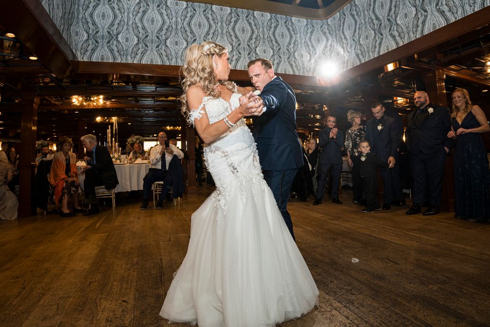 Couples dancing together at an elegant wedding reception with ornate wallpaper and chandeliers.