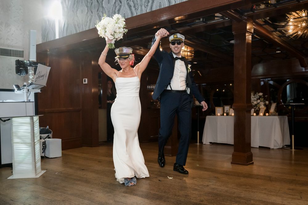 Wedding couple performs their first dance in an elegant wood-paneled reception hall with white decor.