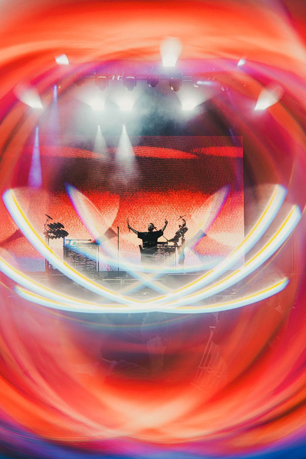 Abstract red and blue swirling patterns create a dynamic tunnel-like effect with silhouettes visible in the distance.