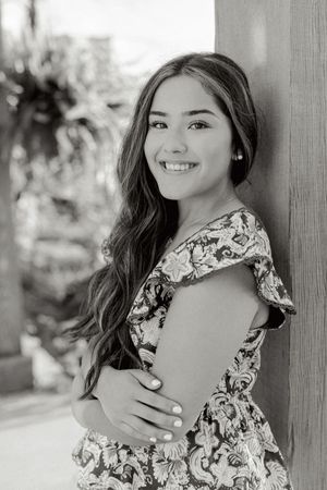Black and white portrait against a wall wearing a patterned dress with ruffled details.