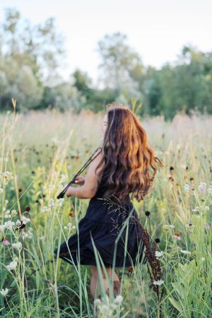 Dynamic movement captured in a flowing black dress among wild summer grasses.