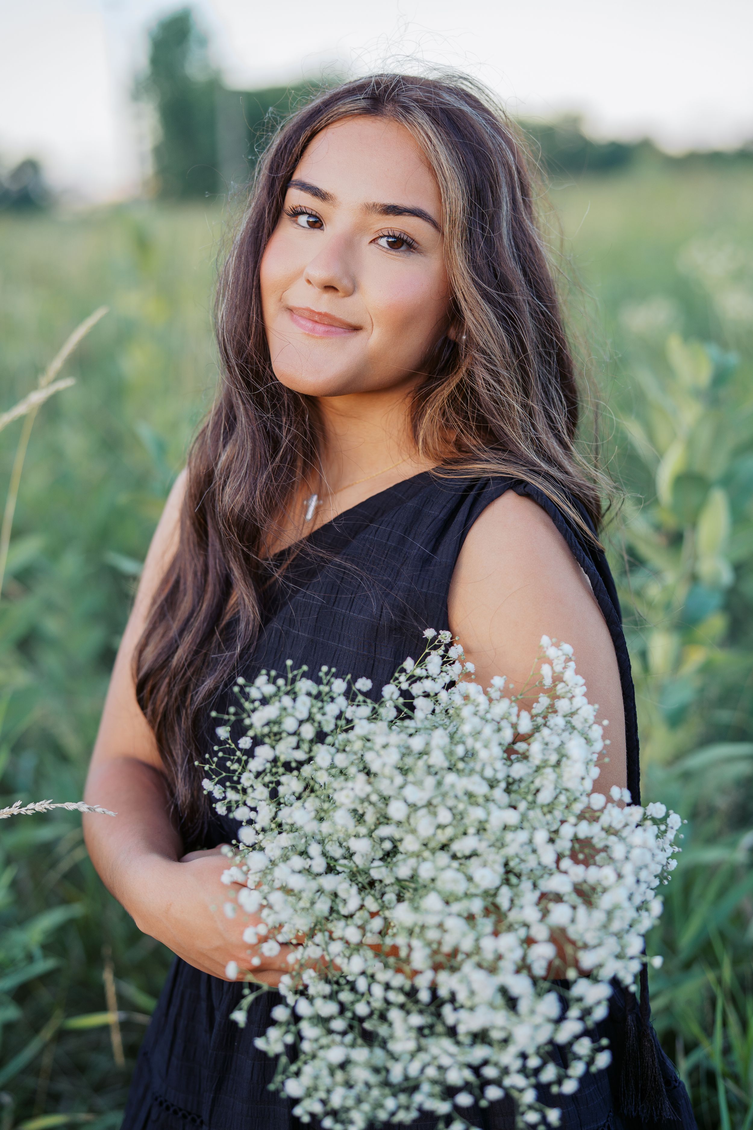 Ethereal portrait series with white baby's breath flowers against a black dress in a meadow setting.