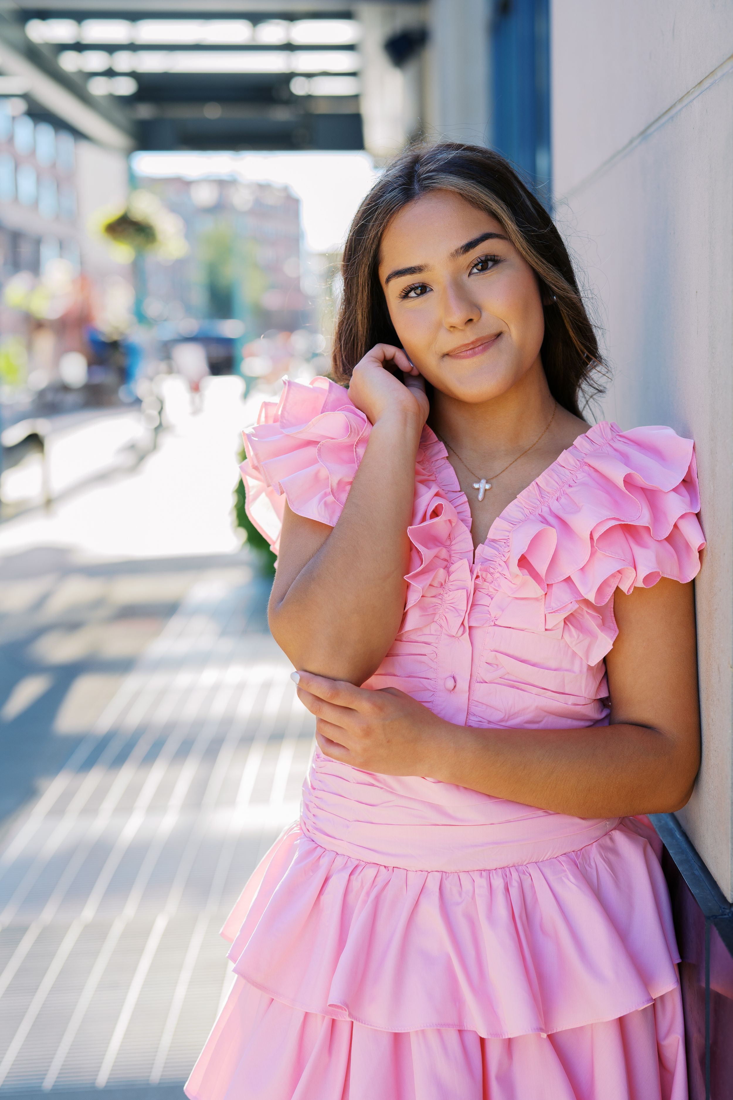 A feminine pink ruffled dress brightens up an urban setting with modern architecture.