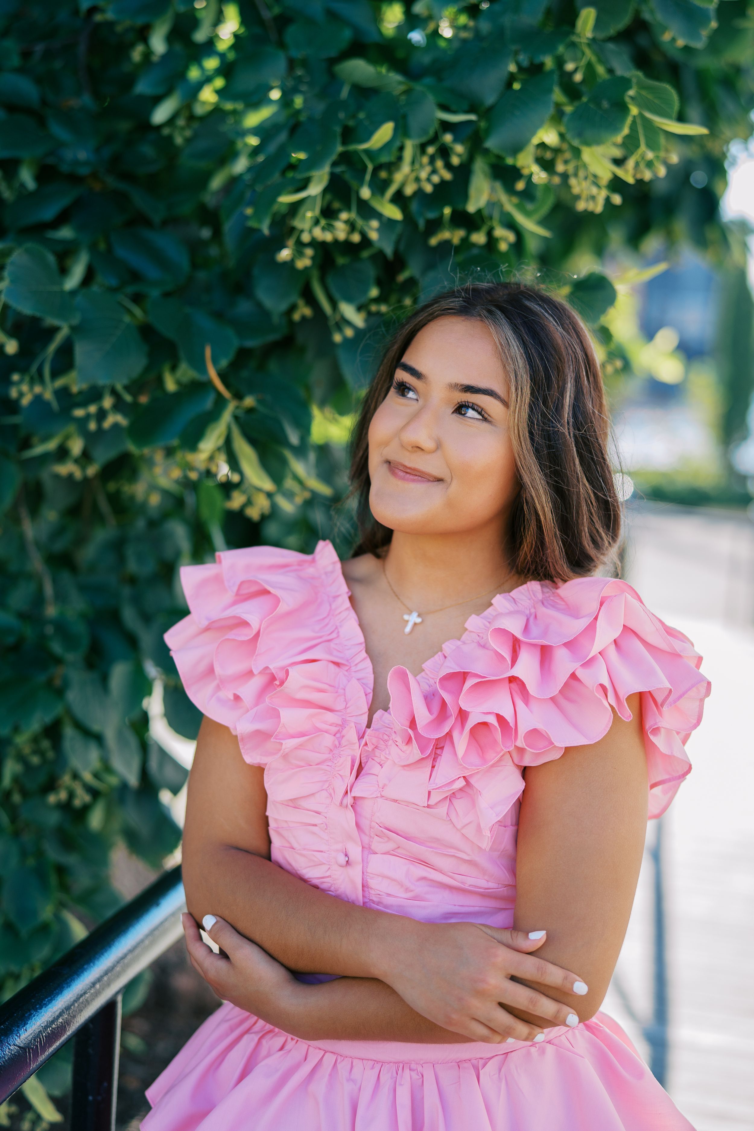 A pink ruffled dress photographed against lush green foliage in natural lighting.