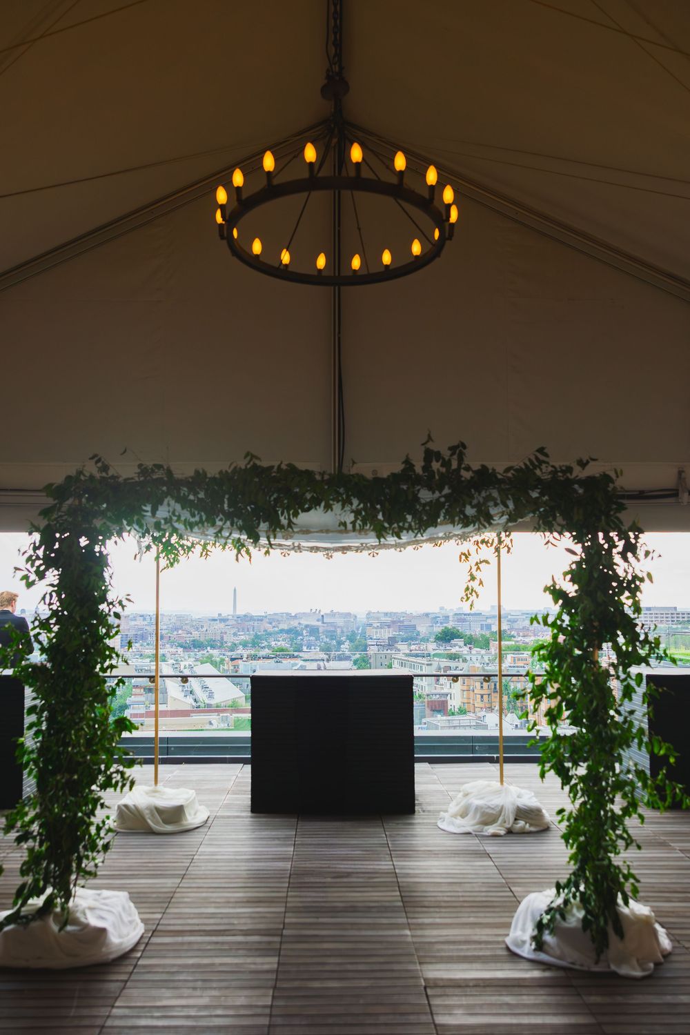 A panoramic rooftop terrace with white lounge seating, circular chandeliers, and climbing plants offers stunning city views at the line DC