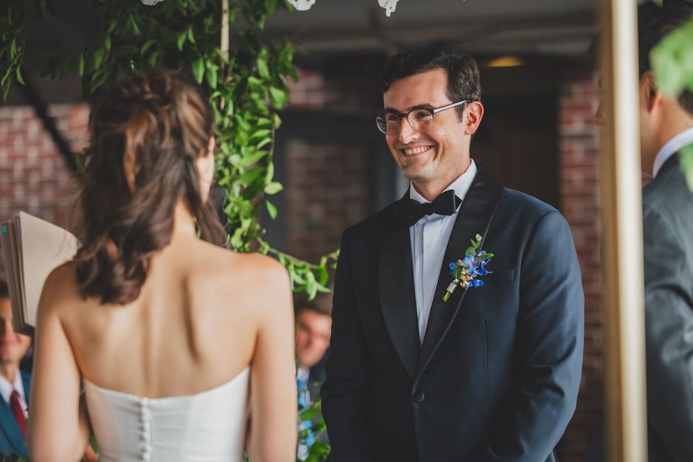 A couple shares an intimate moment during their wedding ceremony while guests look on with smiles.
