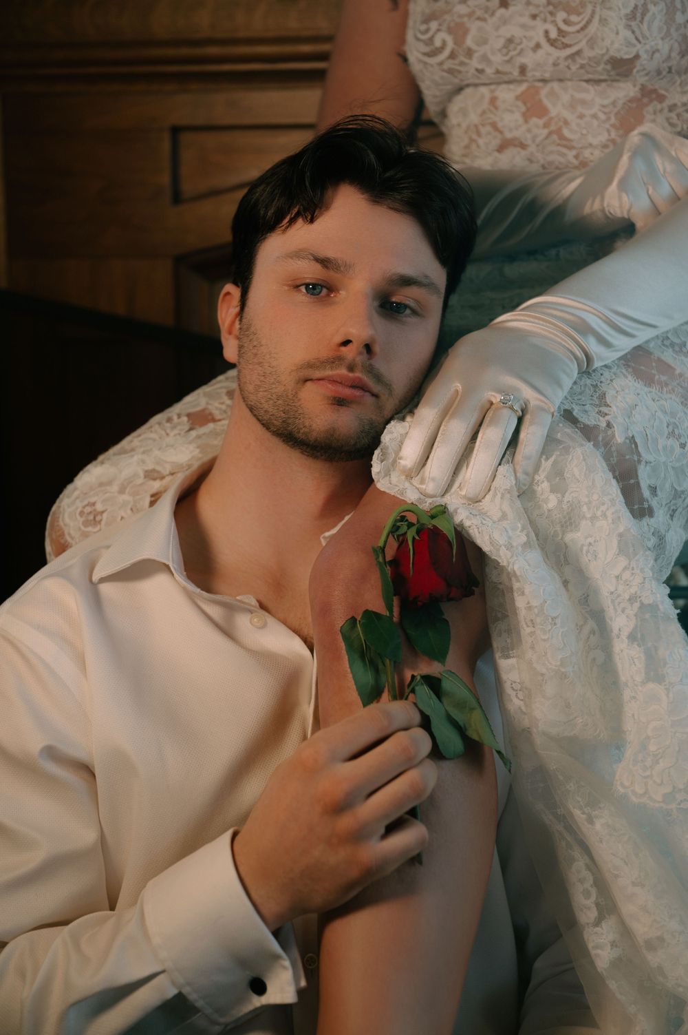 Romantic scene with red rose and white lace dress against soft lighting and intimate atmosphere.
