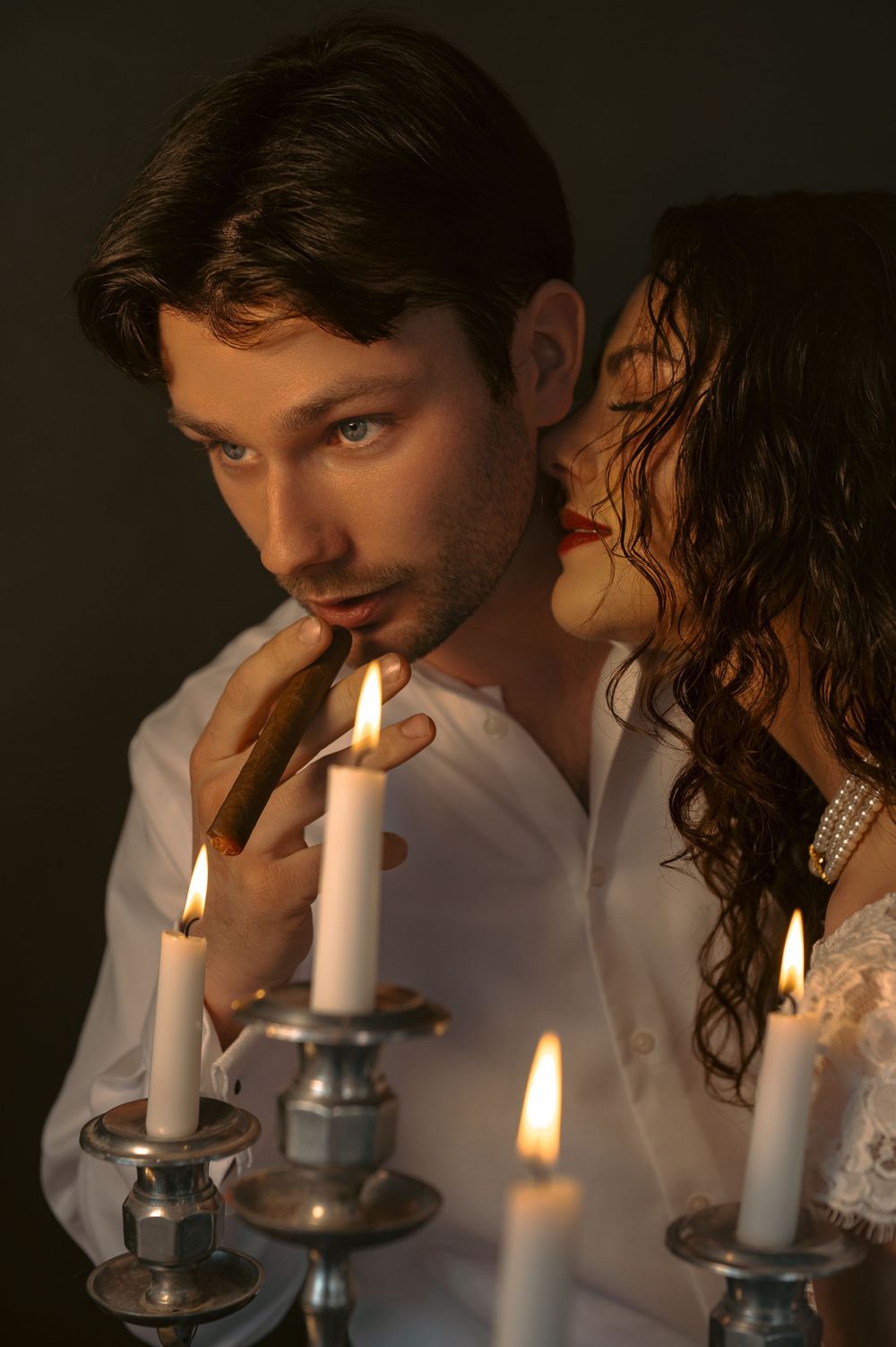 Candlelit scene with white candles in glass holders creating a romantic and moody atmosphere.