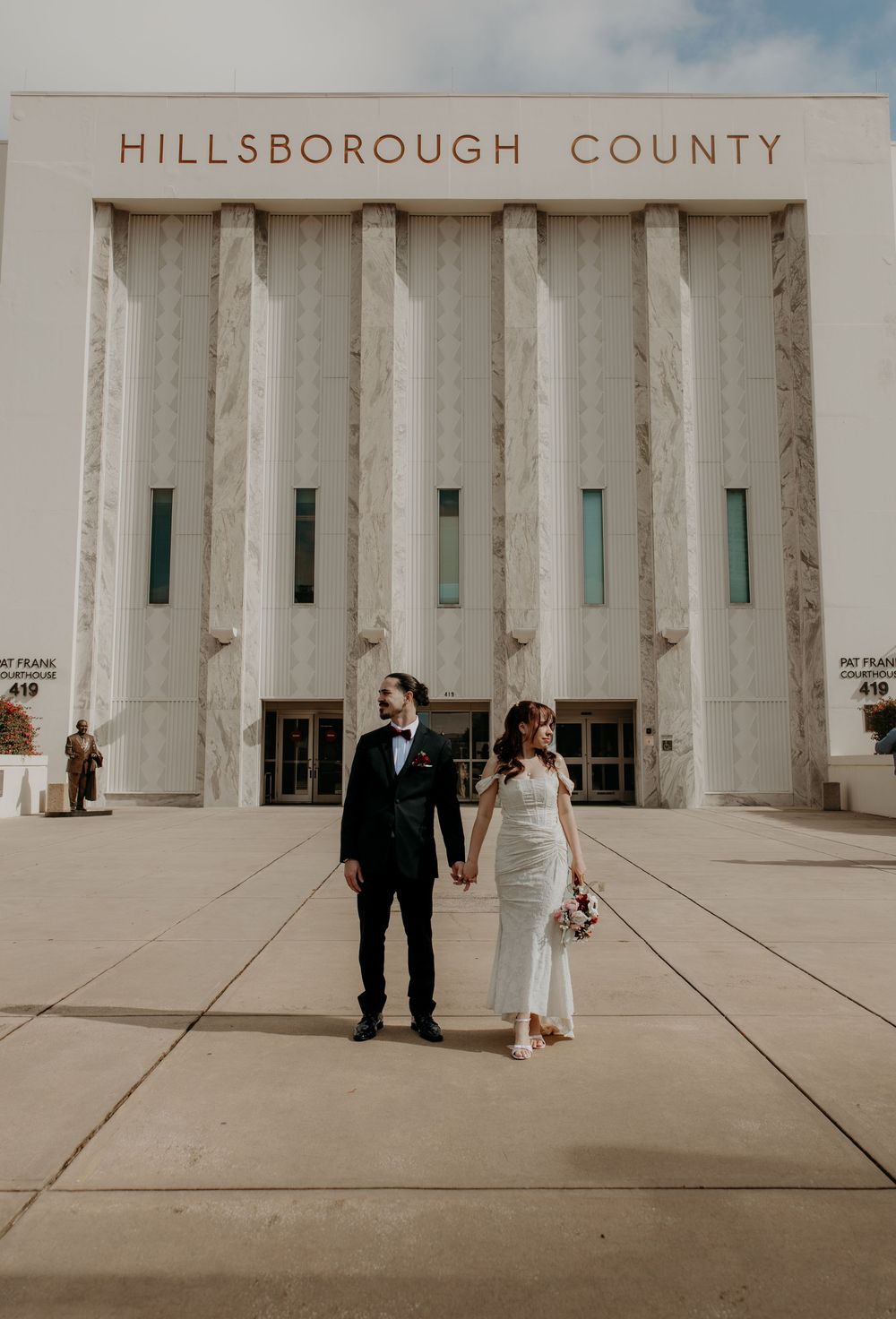 Bride and groom hold hands outside Hillsborough County courthouse on their wedding day.
