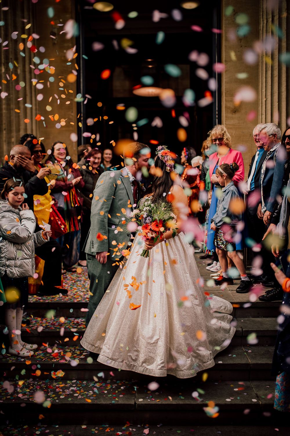 Wedding celebration on church steps with colorful confetti falling as newlyweds exit in a beautiful autumn ceremony.