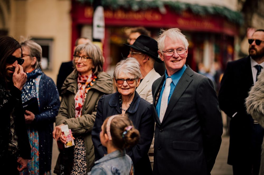 Guests mingle and laugh during a formal event while wearing suits and dresses.