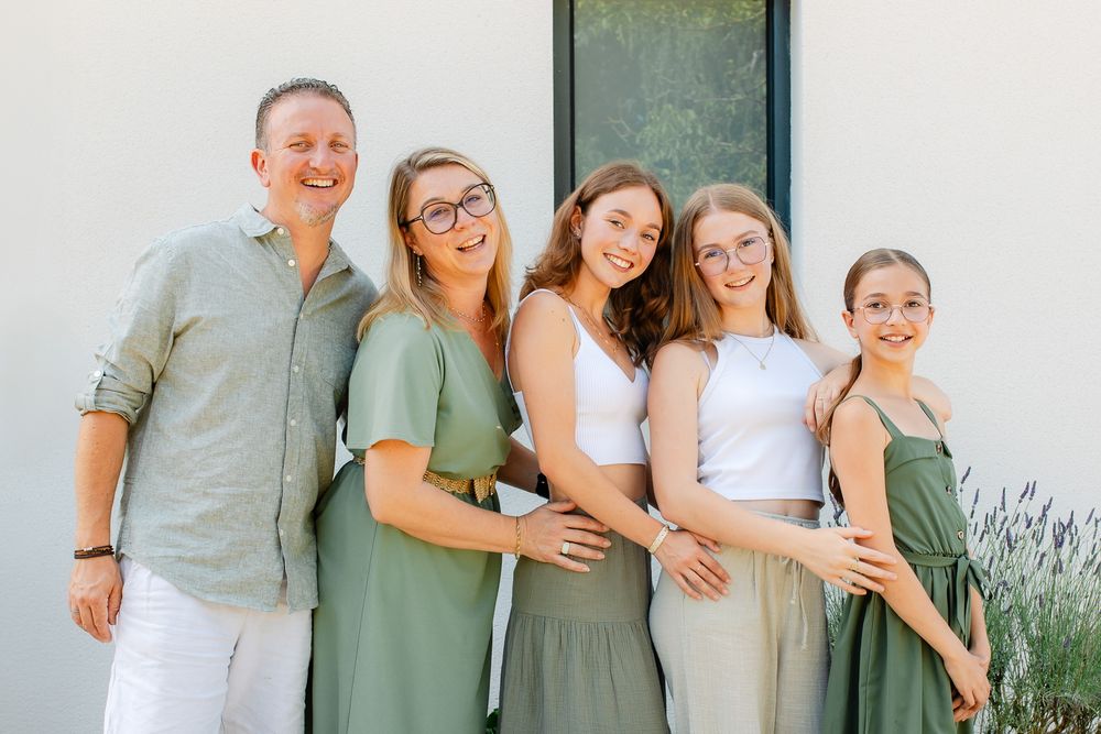 Famille qui pose devant sa maison en extérieur pendant l'été