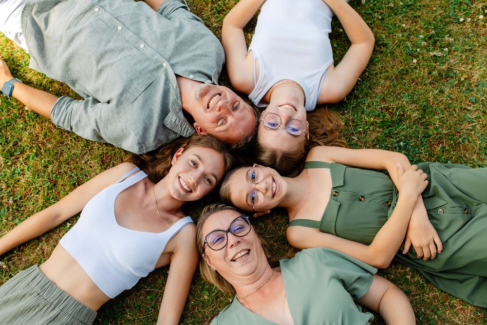 Famille allongée qui pose dans son jardin pendant une séance photo lifestyle