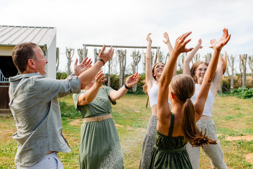 Famille qui joue à faire une bataille d'eau dans son jardin pendant une chaude journée d'été lors d'une séance photo lifestyle