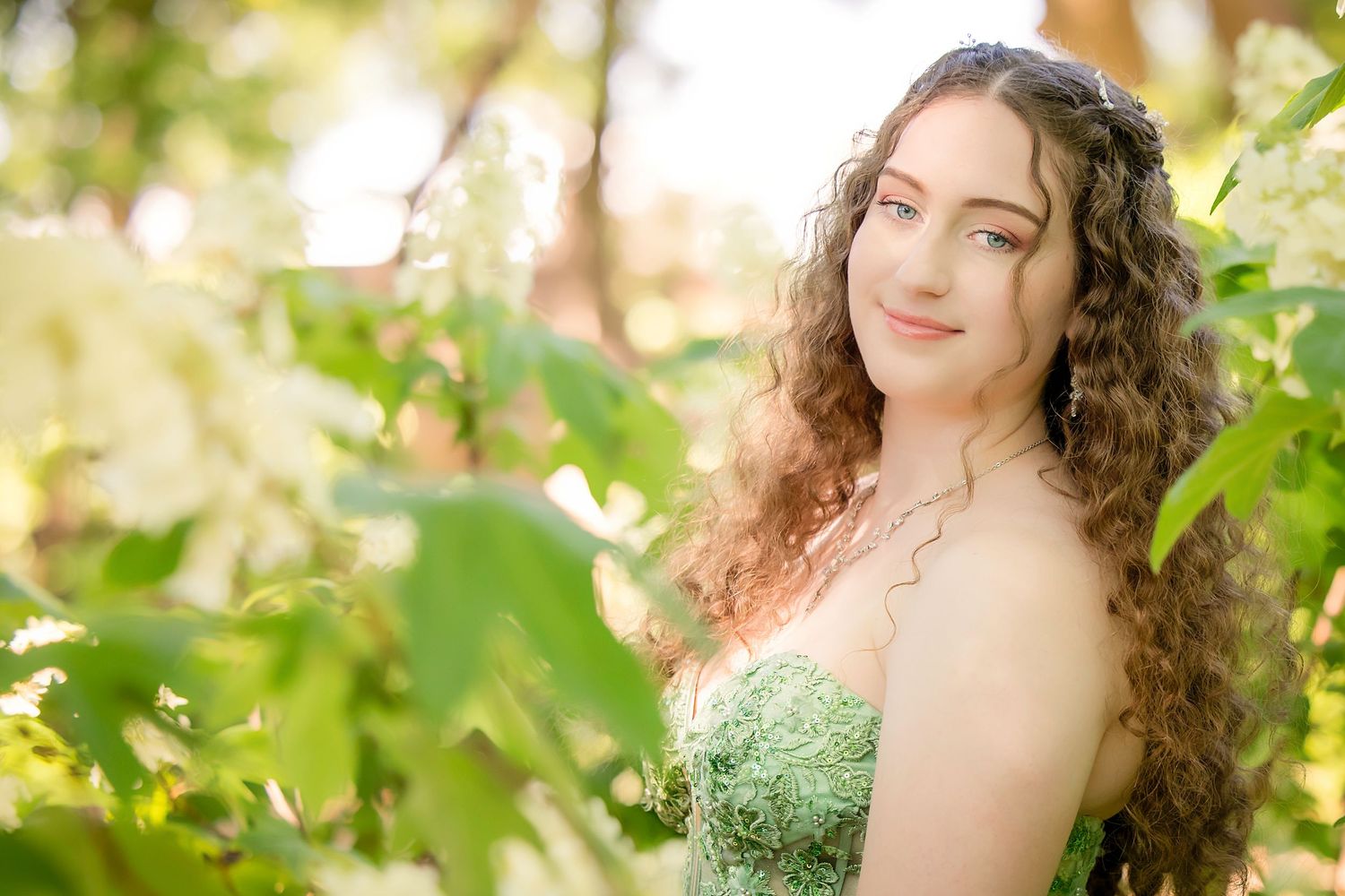 Portrait in a green dress among sunlit leaves and foliage in a dreamy outdoor setting in Grapevine, TX.