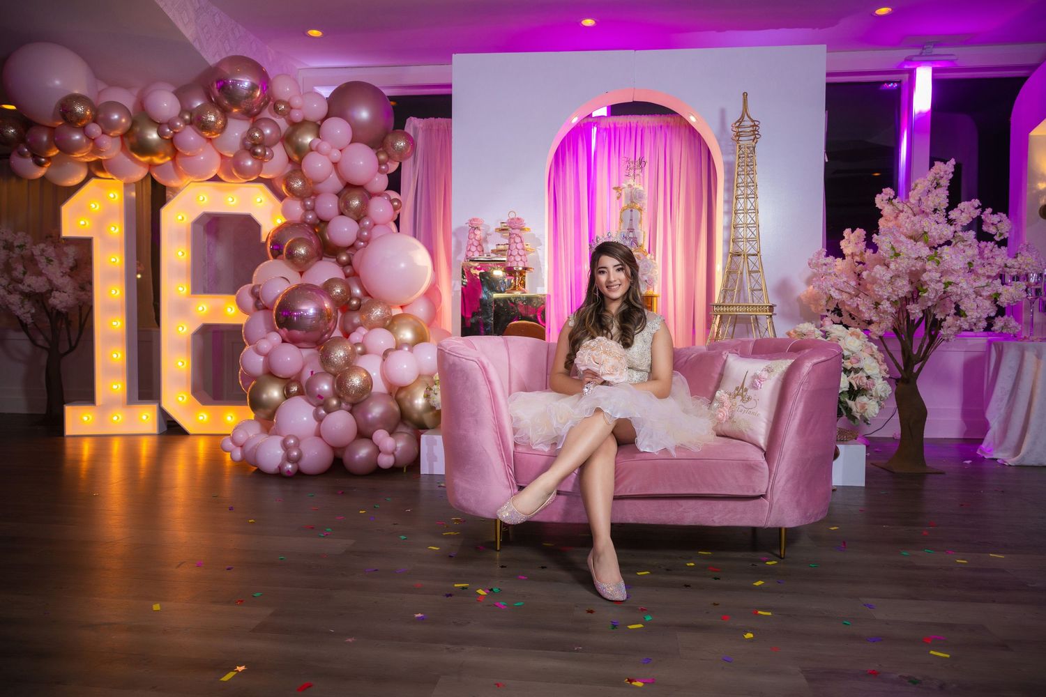 Luxurious pink and gold themed party setup with balloon arch and illuminated number 18 for a birthday celebration.