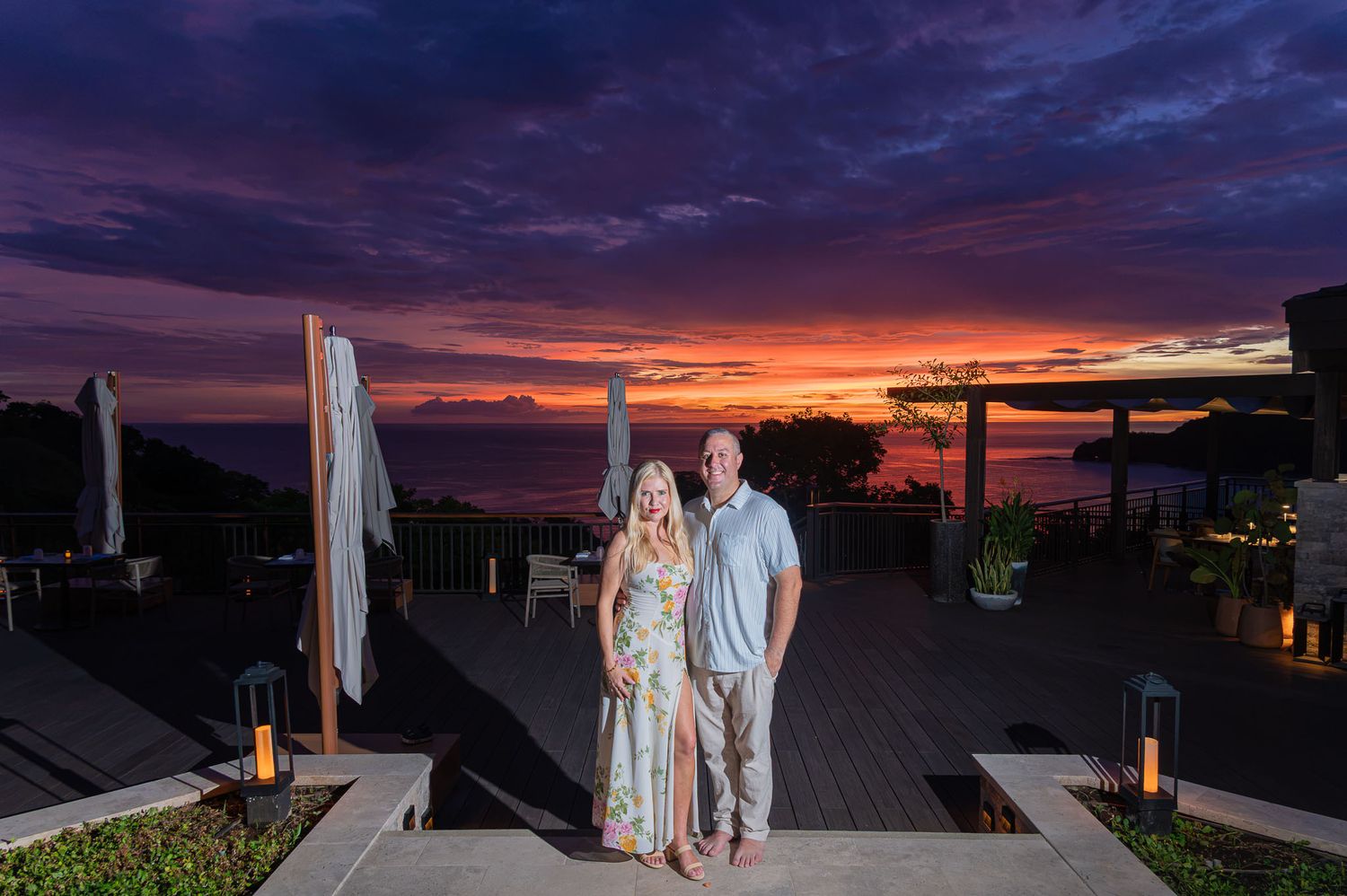 Couple posing at sunset on a tropical terrace with vibrant purple and orange sky over the ocean at Ritz Carlton, Peninsula Papagayo